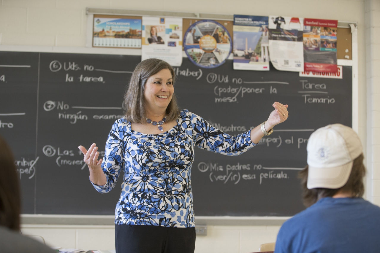 A teacher engages with students from the front of a classroom